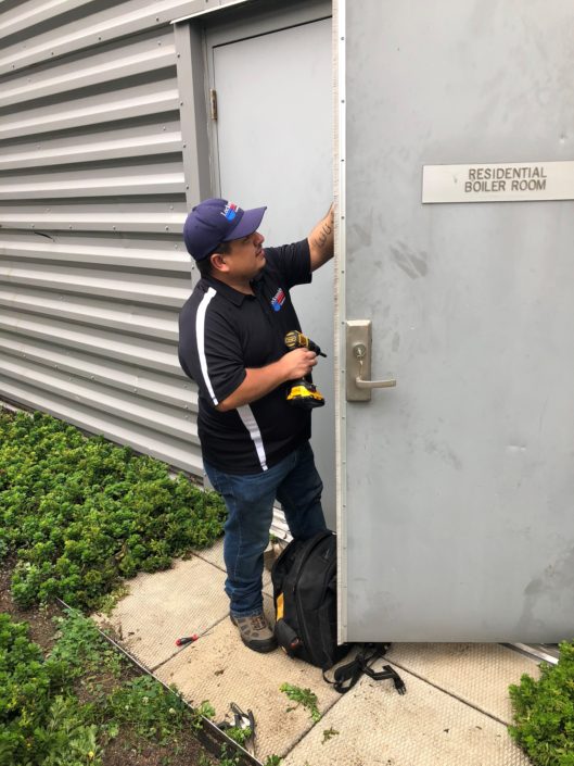 A man in blue hat and black shirt opening a door.